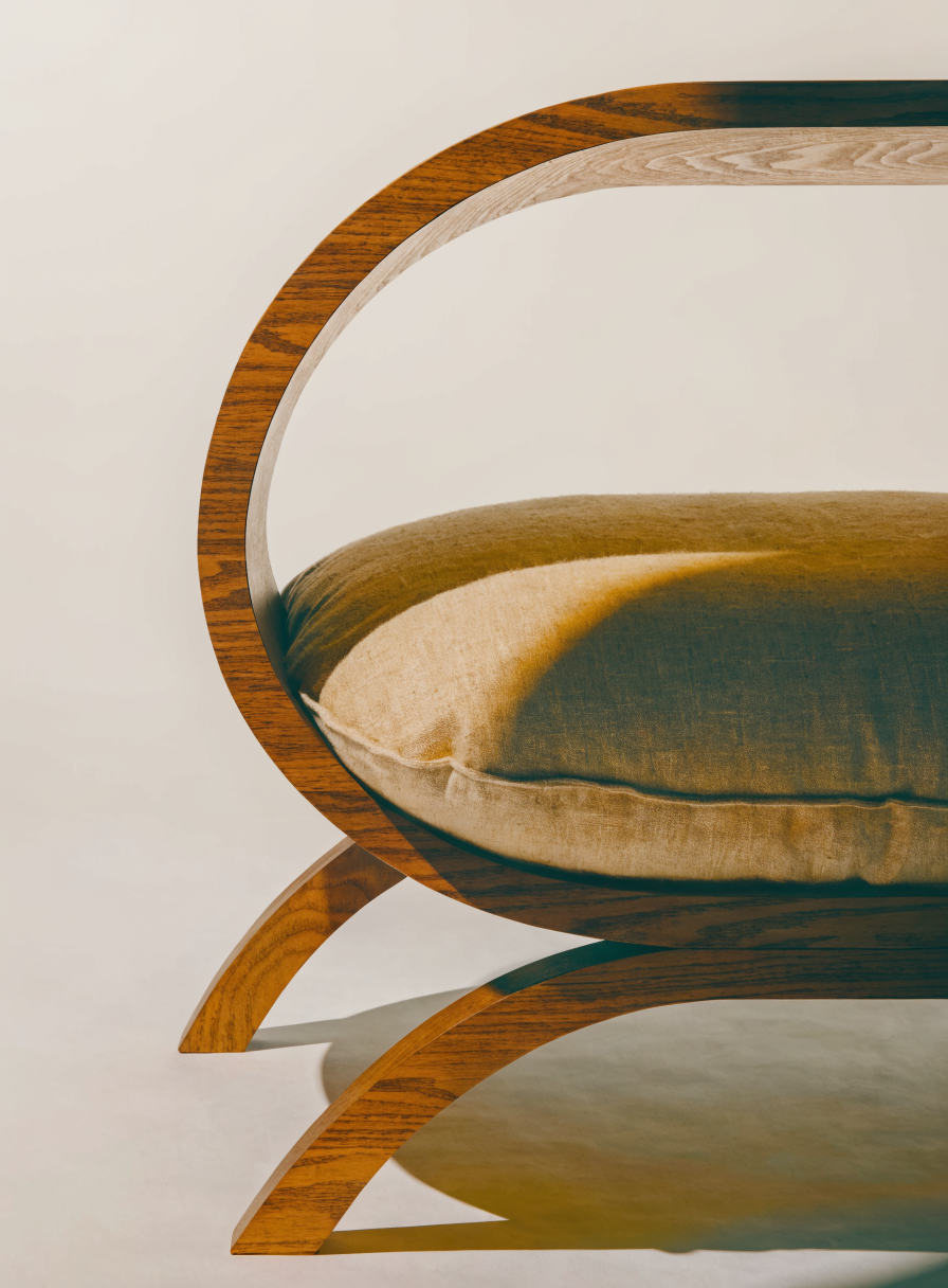 The Arch Bed — walnut timber arch frame with oat linen cushion